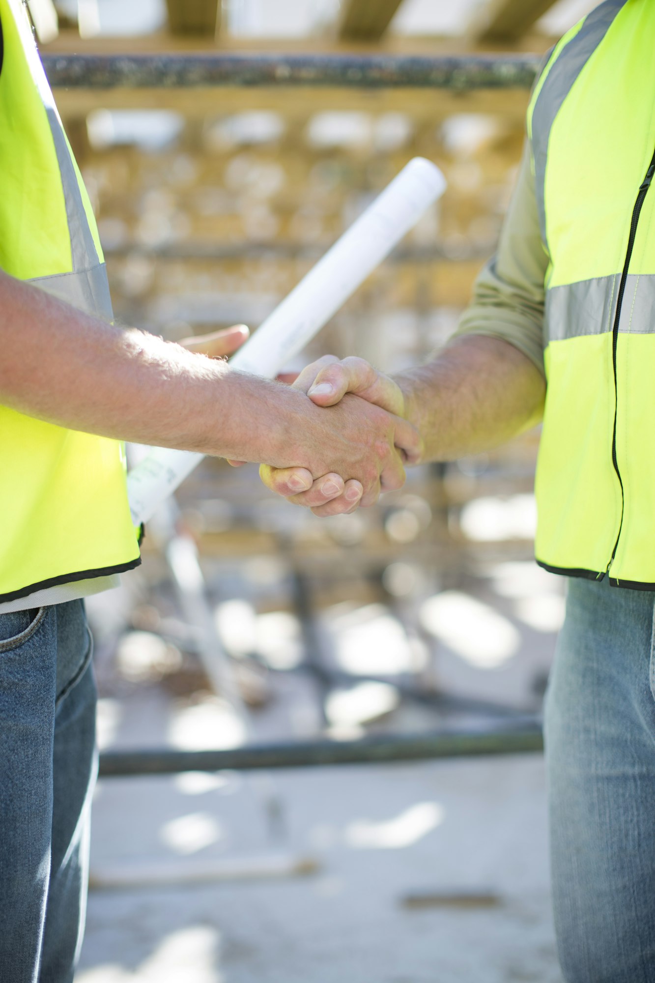 Two construction workers shaking hands in construction site